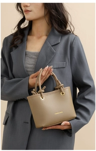 Detail of khaki lychee leather mini bag with knotted handle and gold eyelets on model