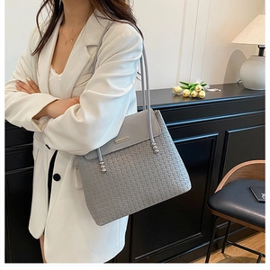 Detailed view of grey woven tote bag with silver ball charms and metallic logo plate