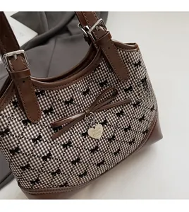 Close-up of brown plaid backpack with bow prints and heart-shaped metal charm detail