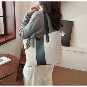 Detail of canvas tote bag with black contrast strap and decorative patterned scarf on handle