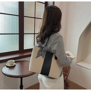 Detail of canvas tote bag with contrast leather trim and silk scarf on a model