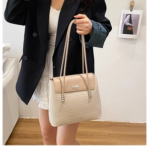 Detail of cream tote bag featuring diamond weave texture and silver logo plaque