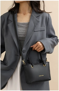 Close-up of black litchi grain leather crossbody bag with elegant gold hardware details