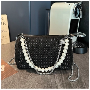 Détail d'un sac de soirée en velours noir orné de strass avec poignée en perles