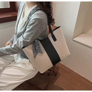 Detail showing the large canvas tote bag with black leather strap and a paisley silk scarf