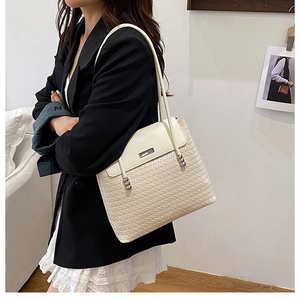 Detail of off-white woven tote bag with leather flap and metal hardware on a shoulder strap