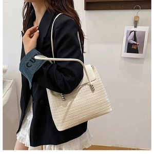 Detail of off-white woven tote bag featuring a metallic sphere buckle on the shoulder strap
