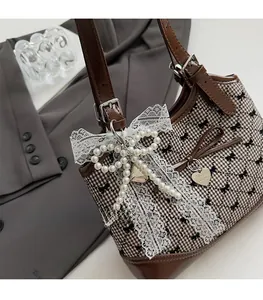 Close-up of retro plaid underarm bag with leather trim and decorative lace pearl bow