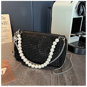 Détail du sac cylindre noir à strass avec chaîne de perles et bandoulière en métal