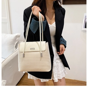 Detail of off-white woven shoulder bag with leather flap and silver spherical metal charm