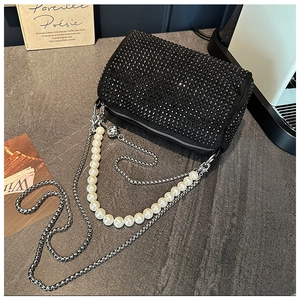 Détail du sac seau en strass noirs avec poignée en perles et chaîne argentée sur pierre