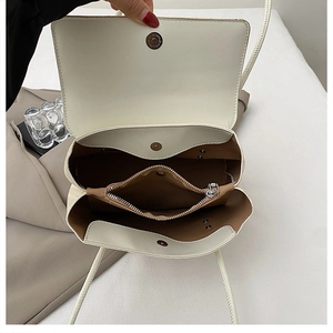 Top view of open beige crossbody bag showing three interior compartments and brown lining