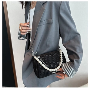 Detail of black rhinestone Boston bag with oversized white pearl chain and metal strap