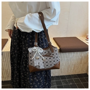 Detail of checkered shoulder bag featuring black bows and heart pendant with lace charm
