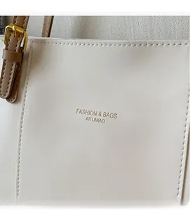 Detail view of cream leather tote with fine texture and gold buckle adjustments