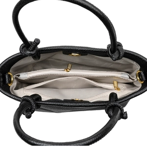 Interior detail of black pebble leather crossbody bag with light grey herringbone lining