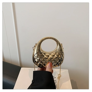Close-up of golden metallic clutch bag featuring a quilted texture and round handle