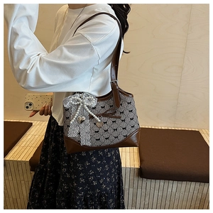Detail of a brown leather shoulder bag with checkerboard pattern and bow decorations
