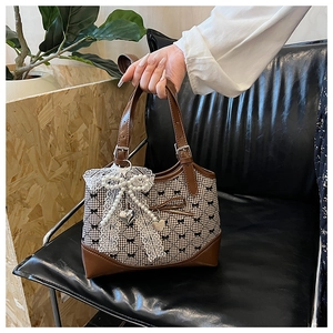 Détail du sac cabas à carreaux avec grand nœud en dentelle et perles et anse en cuir