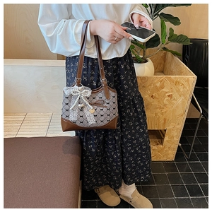 Détail du sac pied-de-poule avec nœud en dentelle et perles et pendentif cœur