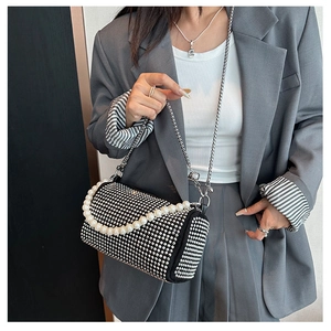 Détail d'un sac cylindrique noir avec strass brillants et une poignée en grosses perles