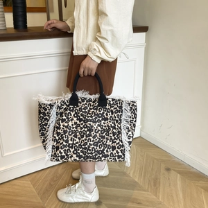 Close-up of leopard print tote bag with white fringe tassels and black handles