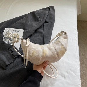 Floral croissant bag in cream and yellow with knot strap shown in minimalist setting