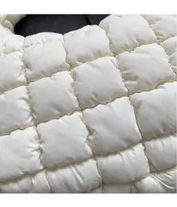 Close-up of white quilted puffer bag showing soft padded nylon texture and detailed stitching