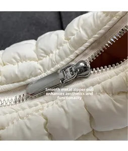 Macro detail of glossy silver metal zipper and white quilted fabric on a puffy bag