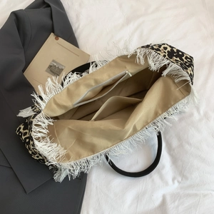 Detail view of large leopard print tote bag interior with zipper pocket and white fringe