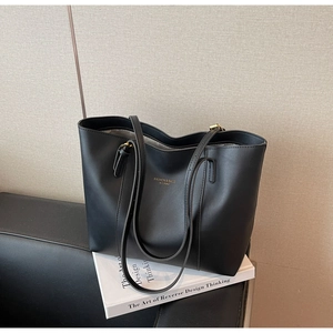 Detailed view of black textured leather tote with gold fashion logo and hardware