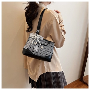 Detail of checkered shoulder bag with lace pearl bow and silver heart pendant