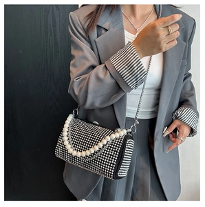 Détail d'un sac bandoulière noir avec strass argentés, perles et bandoulière chaîne