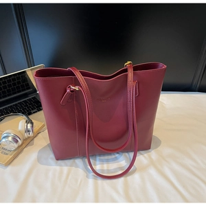 Detail of burgundy leather tote bag with gold logo on a desk with office accessories