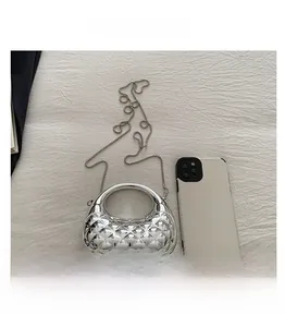 Mini silver handle bag with quilted texture shown next to a smartphone for size scale