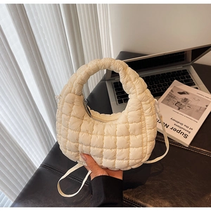Detail showing white quilted bubble fabric and metal zipper of this chic hobo bag