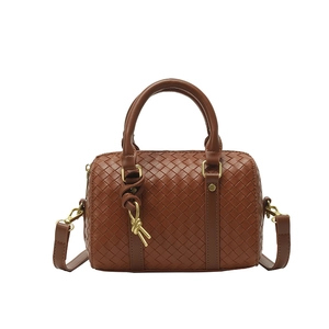 Brown woven leather Boston handbag with round handles and adjustable strap on white background