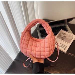 Detailed shot of pink quilted nylon bag with silver zipper on a cozy desktop setting