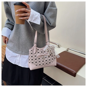 Détail du sac à main rose avec nœuds, breloques perles et dentelle porté par un mannequin