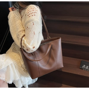 Detail view of large brown faux leather tote bag with Fashion & Bags logo for daily commute
