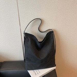 Grande borsa hobo minimalista in tela nera da donna su un libro di design per pendolari