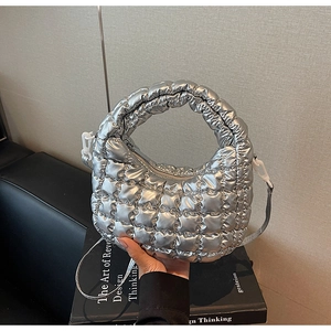 Detail of silver quilted puffer bag showing glossy metallic texture and grid pattern