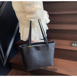 Detail of black leather tote bag showing golden buckle and adjustable shoulder strap