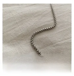 Macro shot of silver metallic square chain link on beige linen fabric detail