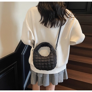 Model wearing a black quilted cloud crossbody bag with soft padded texture on stairs