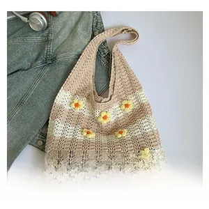 Close-up of beige crochet tote bag with 3D yellow daisies and knit striped texture