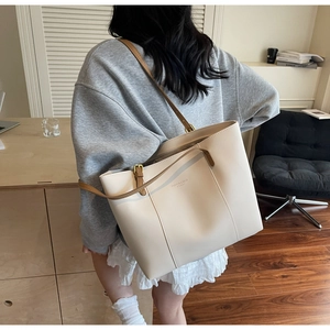 Detail of cream tote bag with brown strap showing back view and fashion embossed text