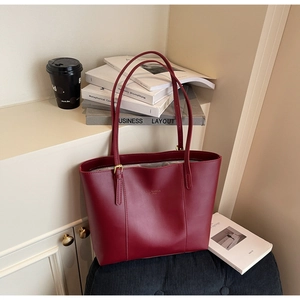 Detail of burgundy tote bag with gold lettering and adjustable metal buckles for daily use
