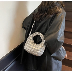 Silver quilted dumpling bag with metallic finish shown on model in a stylish street setting