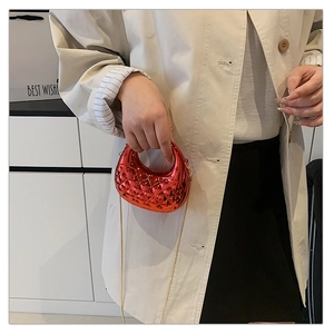Detail of red metallic crossbody bag with diamond quilting and gold chain strap